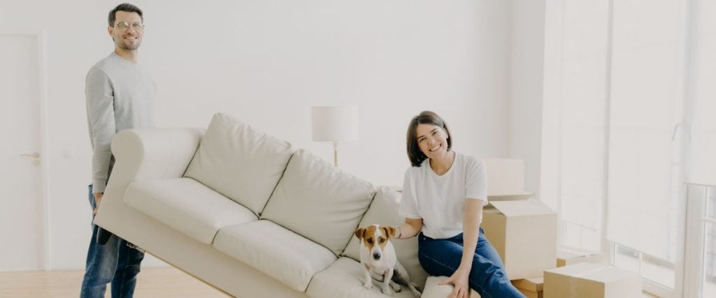 A picture of a man lifting a couch with a woman seated on the opposite side: outdoor furniture features